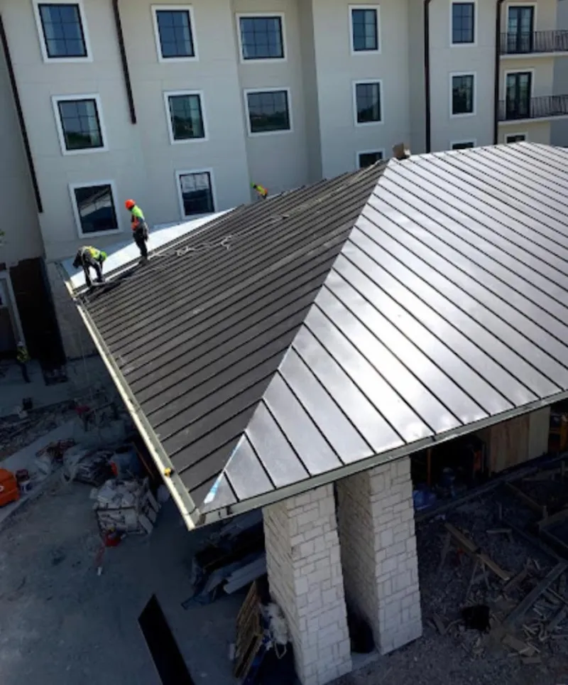 Crew installing standing seam metal roof panels on a commercial project in Lakewood